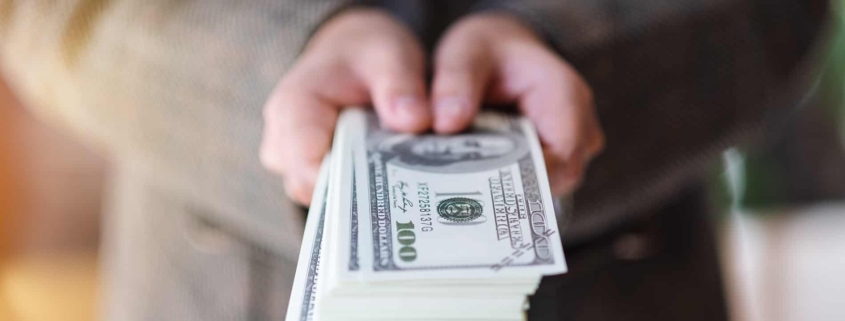 a woman holding and showing American dollar banknotes for money