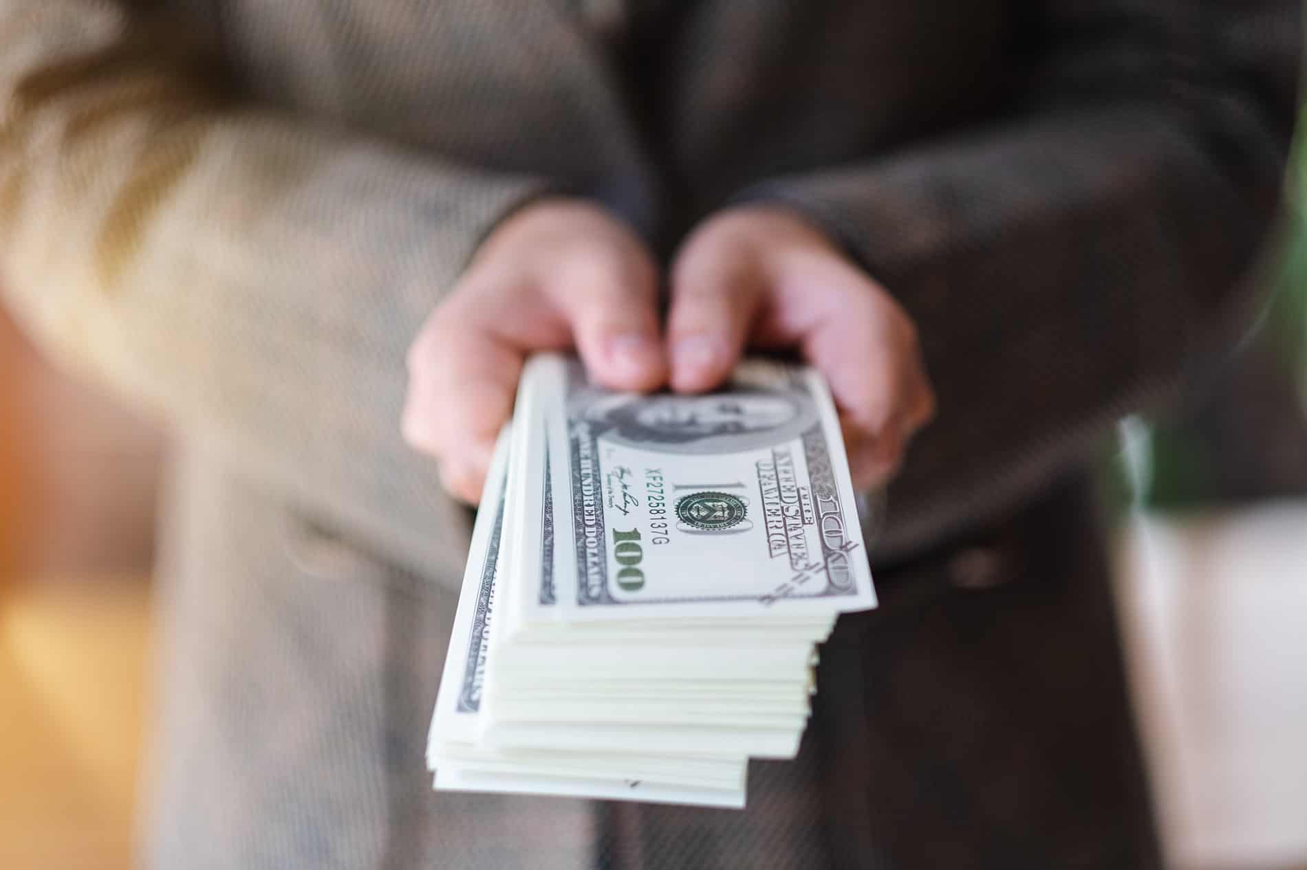 a woman holding and showing American dollar banknotes for money