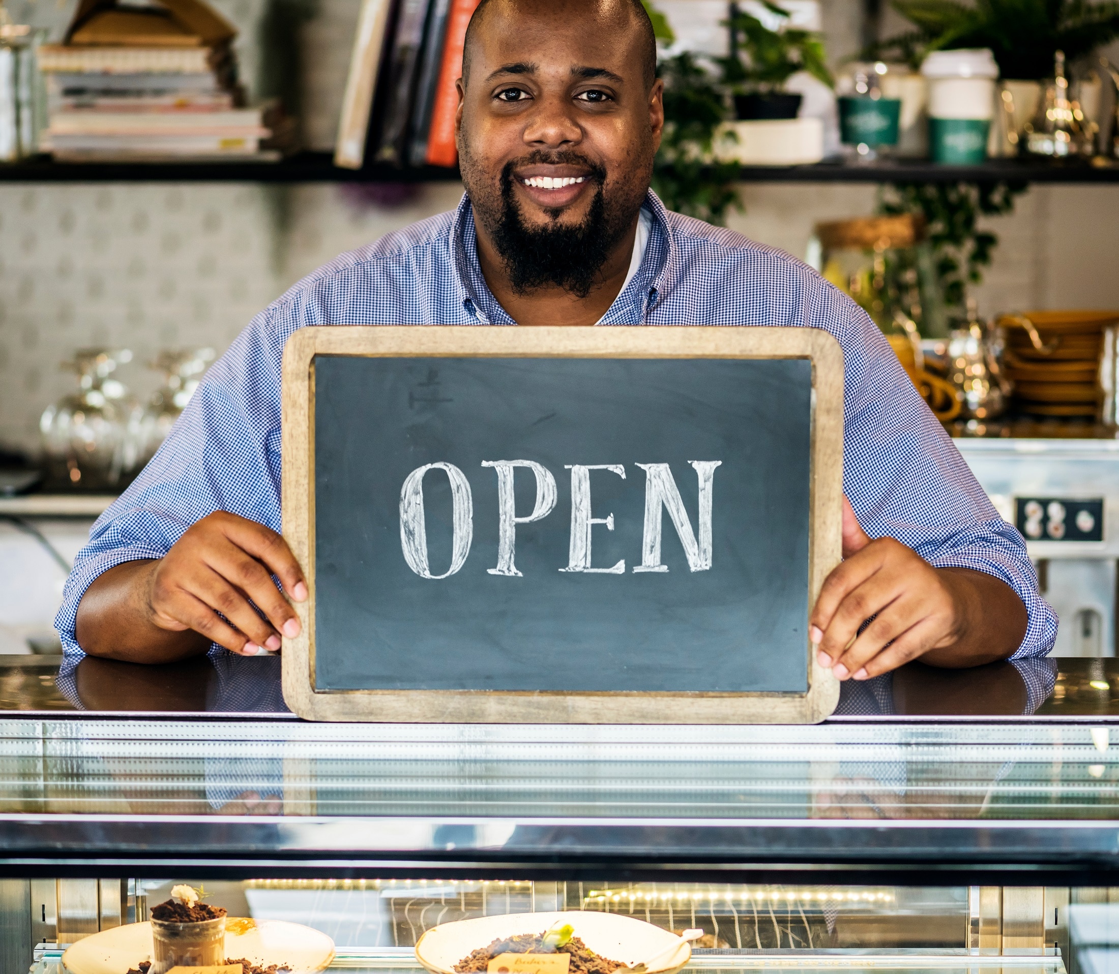 Food Shop Owner Holding Up Open Sign Indicating He's Open For Business
